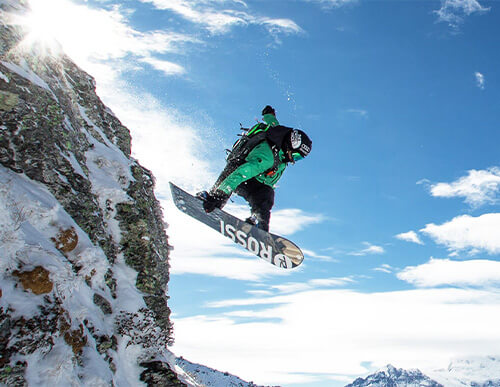 Snowboardeur sautant d'une falaise enneigée
